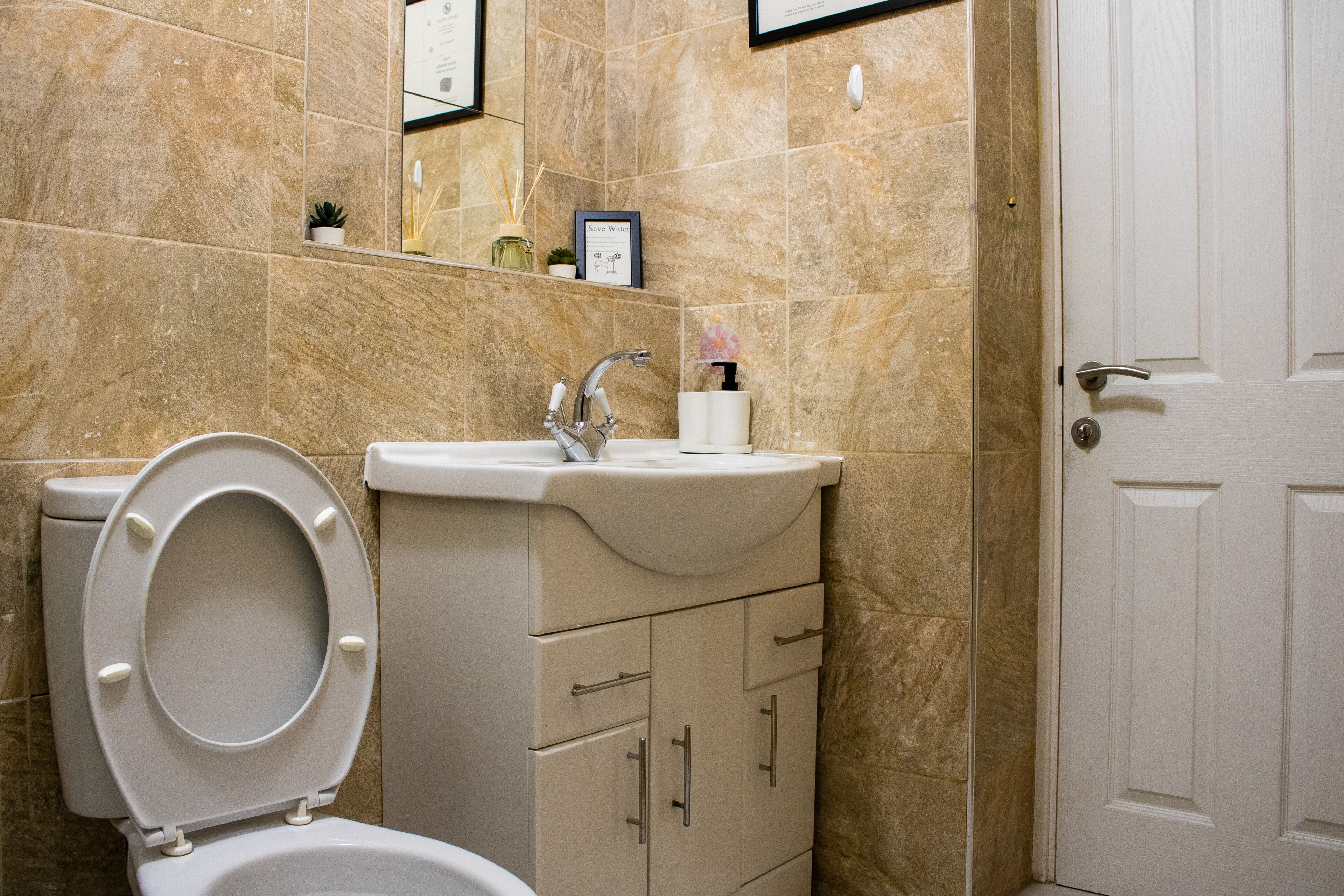 A bathroom with a toilet, sink, and cabinet.