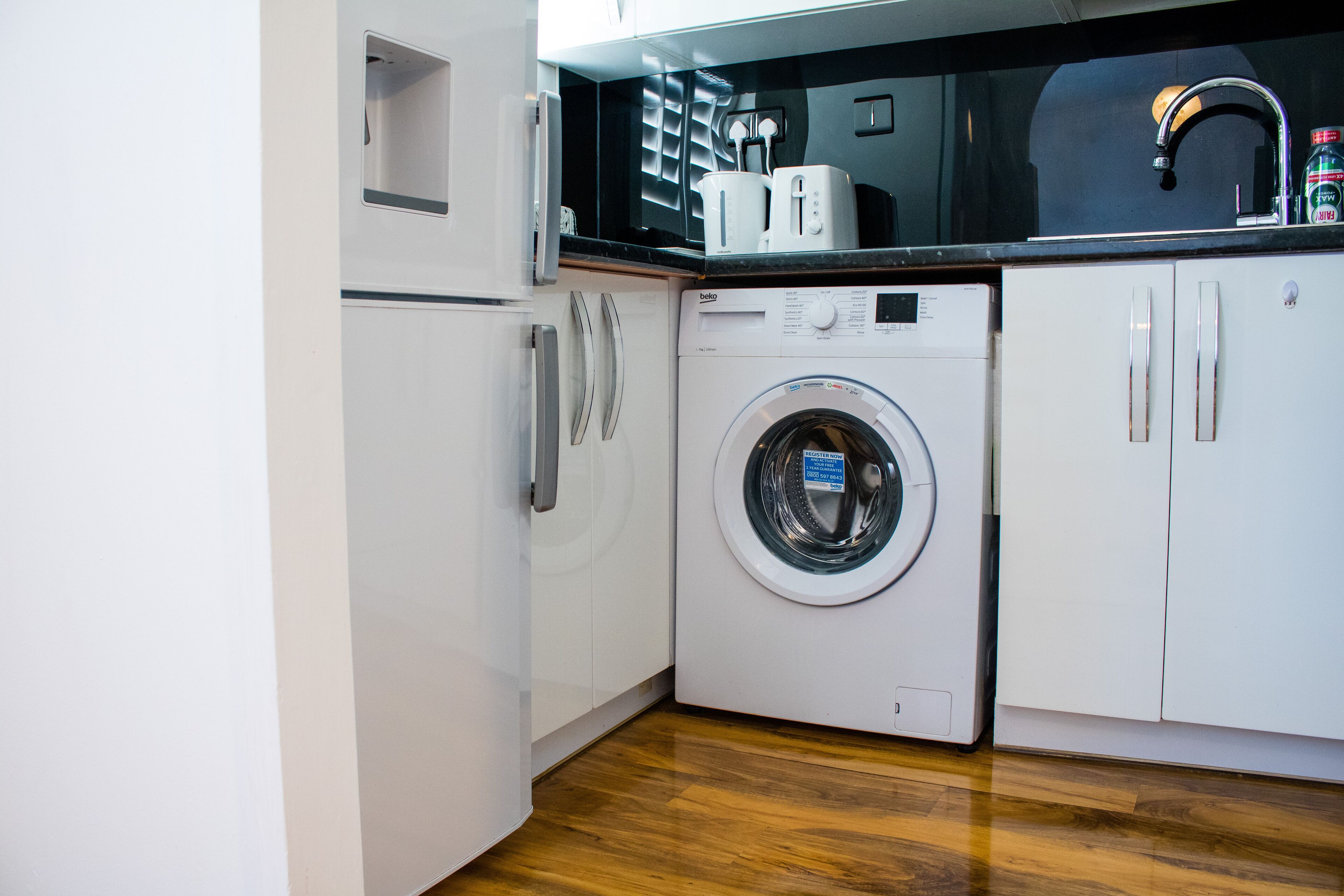 Una cocina compacta con lavadora y secadora integradas, microondas y pileta.