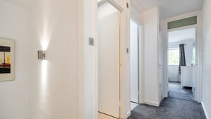 A hallway with white walls, a grey carpet, and a door leading to a bathroom. - Wandsworth Retreat: Spacious Quiet 2BR 2Bth Duplex + View + Nr Trains To Center! (London)