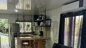 Une cuisine moderne avec un îlot central, des tabourets de bar et un canapé gris.