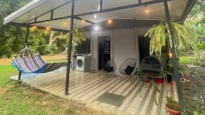 Un espace extérieur abrité, équipé d’un hamac, de chaises et d’un barbecue.