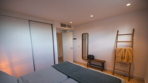 A bedroom with a bed, a mirror, a bench, and a ladder.