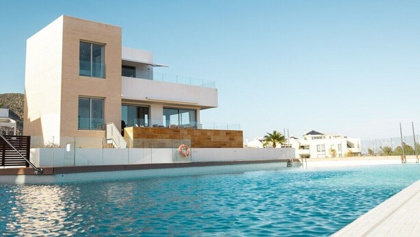 A modern two-story building with a swimming pool in front.