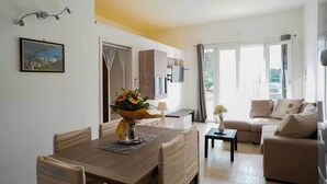 A modern living room with a dining area, a sofa, and a TV mounted on the wall. - 3724 All' Ombra Degli Ulivi by Barbarhouse (Latiano)