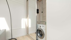 Une buanderie équipée d’un lave-linge à chargement frontal, d’un étendoir et d’un grand lampadaire.