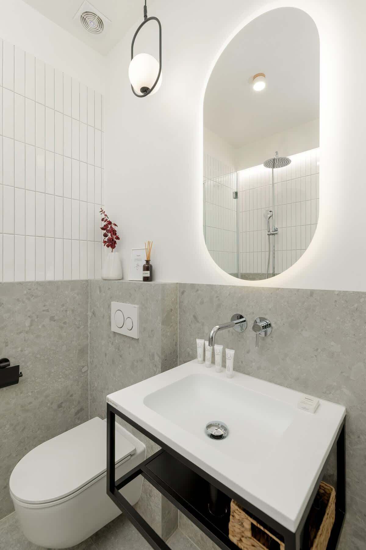 A modern bathroom with a white sink, a toilet, and a shower.