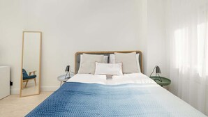 Une chambre à coucher moderne avec un lit, un miroir, une chaise et une petite table.