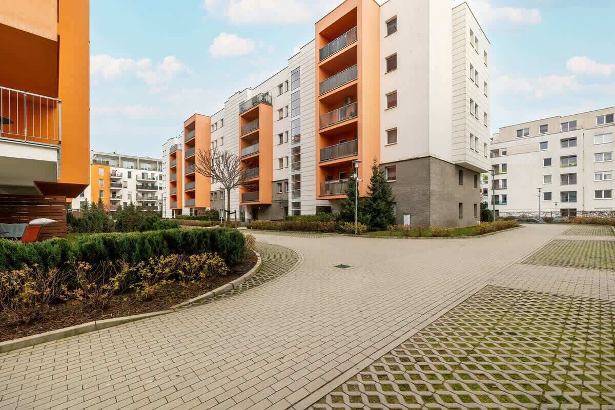 A modern apartment complex with multiple buildings, paved walkways, and landscaped areas.