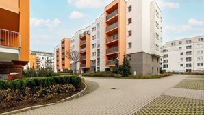 A modern apartment complex with multiple buildings, paved walkways, and landscaped areas. - Stylish Apartment with Balcony | Guaranteed Parking (Poznan)