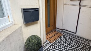 Une porte avec un paillasson, une boîte aux lettres et un sol carrelé.