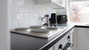 Een moderne keuken met een gasfornuis, een koffiezetapparaat en een raam met uitzicht op de stad.