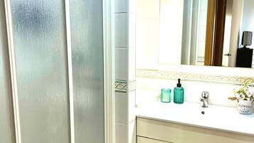 Un bany amb un lavabo blanc, un mirall i un armari.