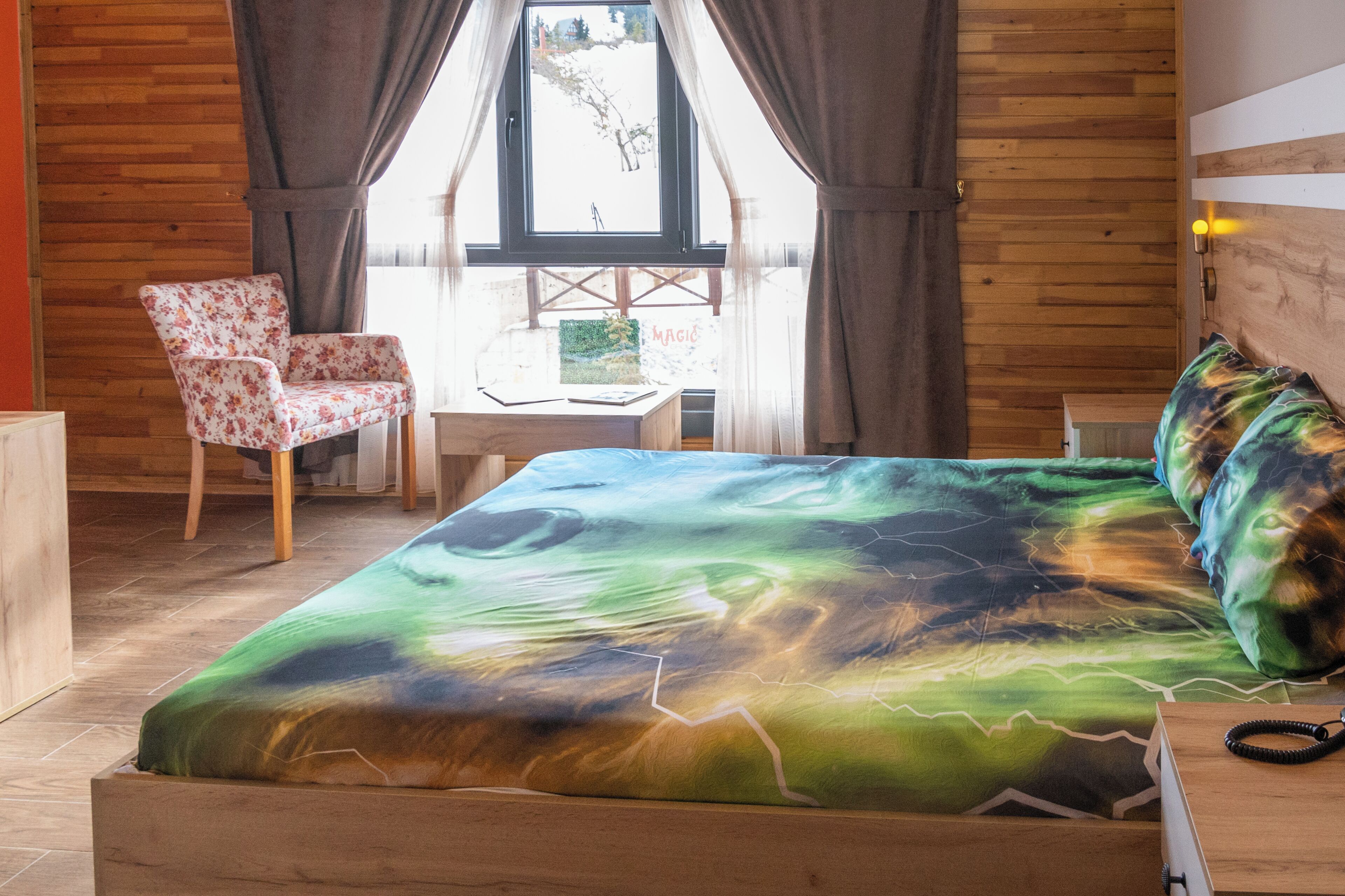 A bedroom with a bed, a chair, a desk, and a window.