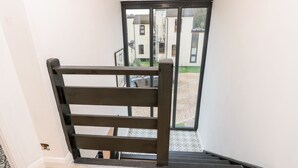 A staircase with a wooden handrail leading to a glass door. - Creek Lodge (Ryde)