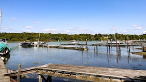 A marina with boats docked, wooden piers, and a forested hill in the background. - Creek Lodge (Ryde)