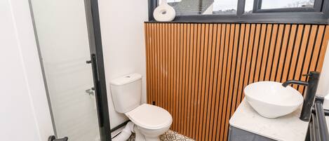 Un baño pequeño con inodoro, lavabo y zona de ducha.