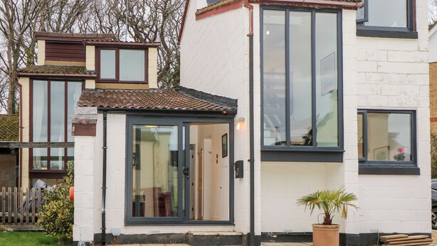 A modern two-story house with a tiled roof, large windows, and a small front garden with a potted plant. - Creek Lodge (Ryde)