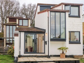 A modern two-story house with a tiled roof, large windows, and a small front garden with a potted plant. - Creek Lodge (Ryde)