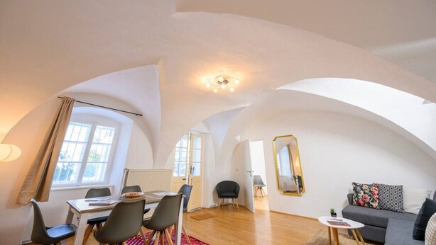 A spacious loft apartment with high ceilings, a dining area, a sofa, and a large mirror. - City Center Mödling top 1 (Mödling)