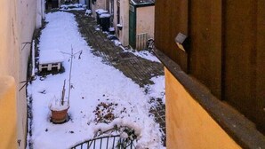 A narrow alleyway with snow on the ground, flanked by buildings with multiple stories and windows. - City Center Mödling top 1 (Mödling)