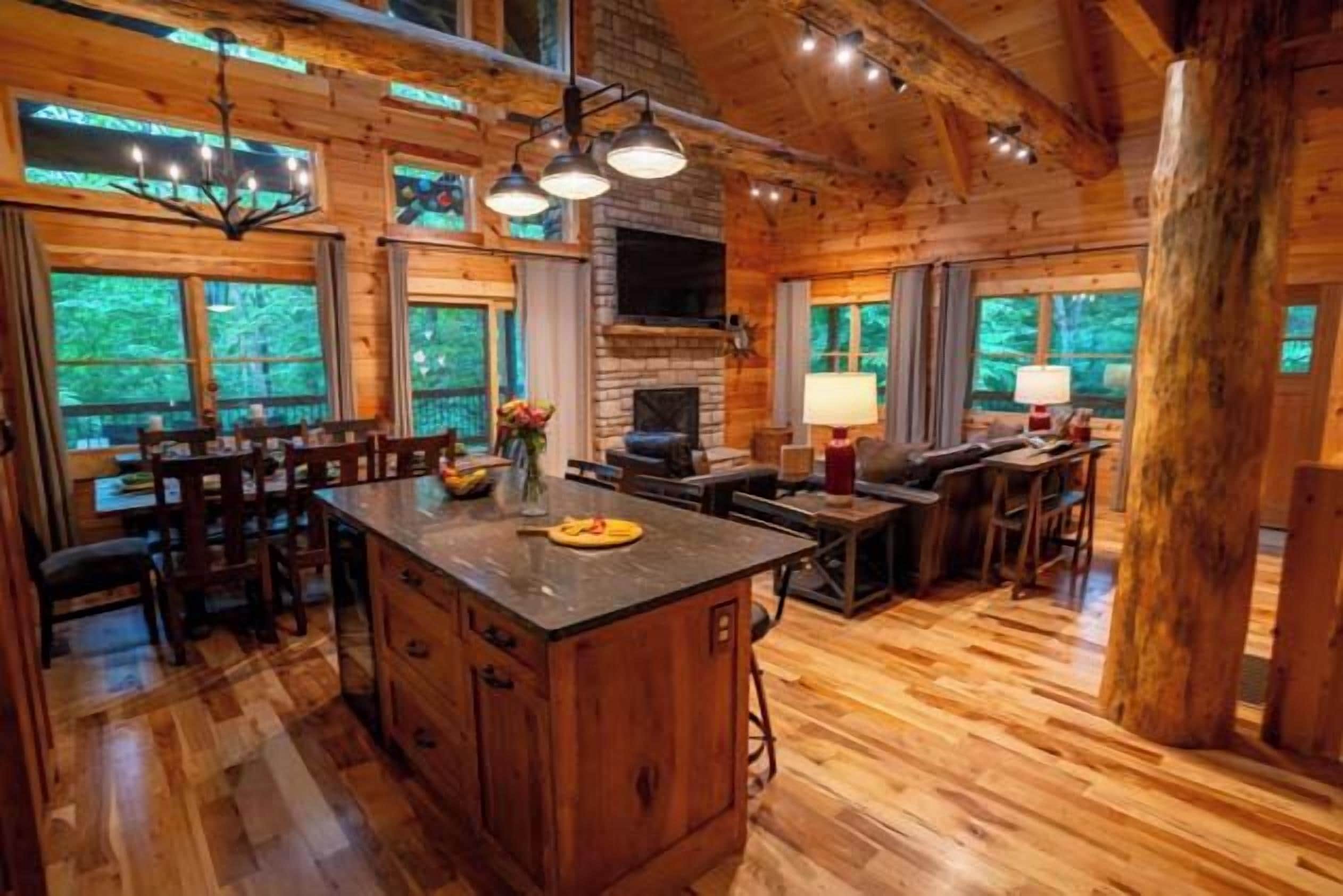 A spacious wooden cabin interior with a large island, dining area, and a fireplace.