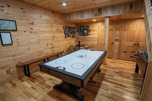 Una habitación con piso de madera, una mesa de billar, armarios de madera y cuadros en la pared.