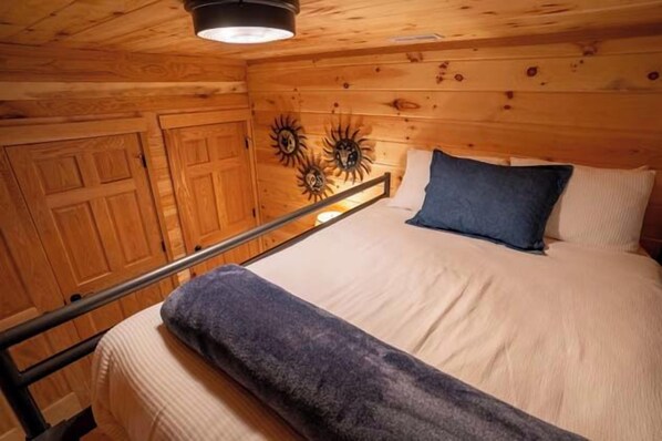 A wooden cabin bedroom with a bed, a nightstand, and a headboard. - Honey Goat Hill, Sleeps 10, Centrally Located with Wooded Views (Logan)