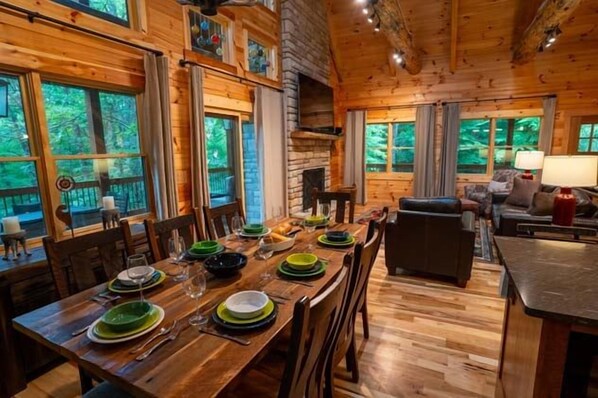 A wooden dining area with a long table set for a meal, surrounded by chairs. - Honey Goat Hill, Sleeps 10, Centrally Located with Wooded Views (Logan)