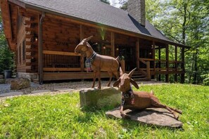 A wooden cabin with a porch, a goat statue, and a log cabin-style exterior. - Honey Goat Hill, Sleeps 10, Centrally Located with Wooded Views (Logan)