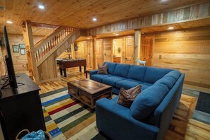 A wooden interior with a blue sofa, a coffee table, and a staircase. - Honey Goat Hill, Sleeps 10, Centrally Located with Wooded Views (Logan)