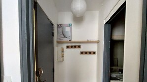 A narrow hallway with a carpeted floor, a white ceiling light, and a door on the left.