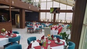 A restaurant with tables set for dining, featuring a modern interior with blue chairs and red tablecloths. - LB Suites Hotel (Bir El Djir)