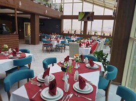 Un restaurante con mesas dispuestas para comer, con una decoración moderna, sillas azules y manteles rojos.