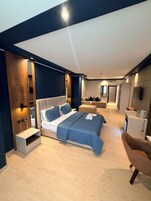 Una habitación de hotel moderna con una cama grande, un escritorio y una zona de estar.