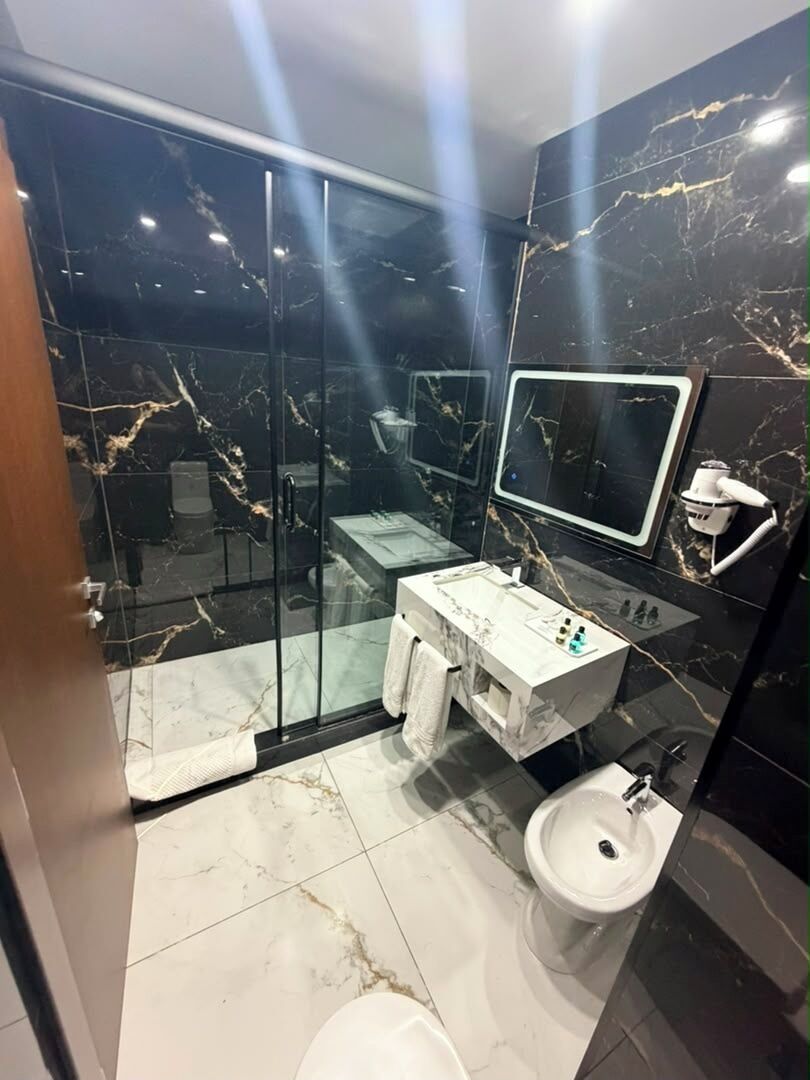 Une salle de bain moderne avec une douche à parois de verre, un lavabo blanc et un grand miroir.