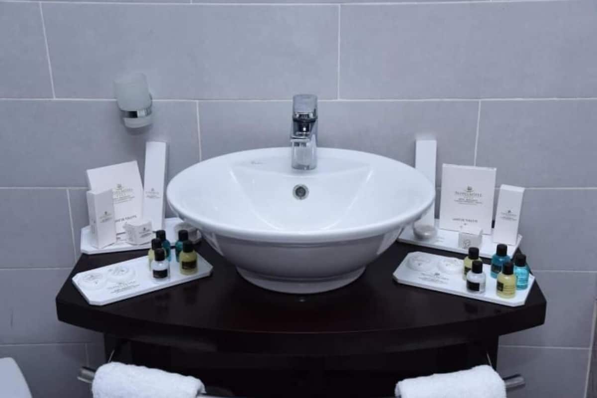Ein Badezimmer mit weißem Waschbecken, schwarzer Arbeitsplatte und Pflegeprodukten.