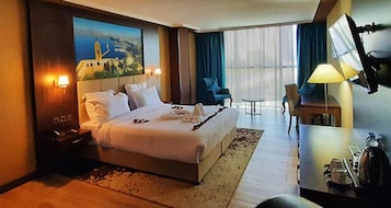 Una habitación de hotel con una cama grande, un escritorio con lámpara, una silla y un televisor.