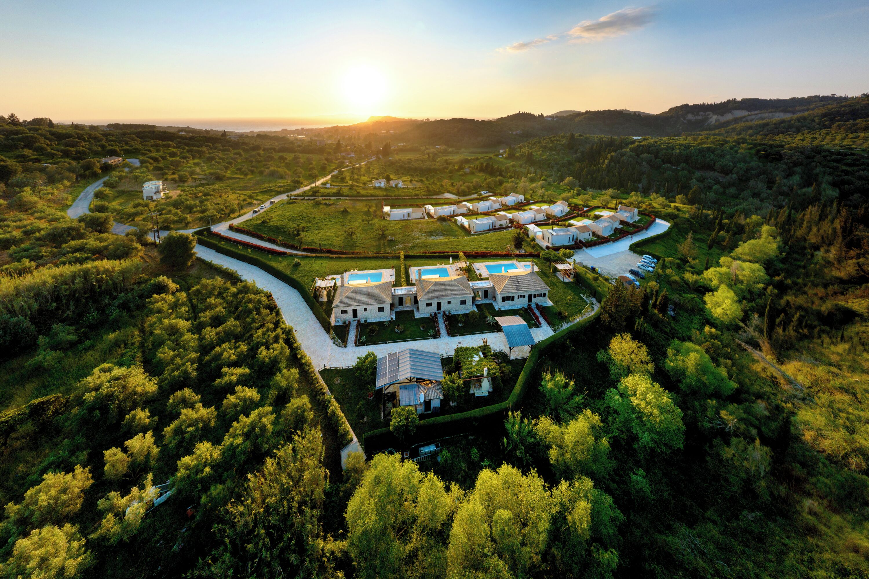 An aerial view of a residential area with houses, a swimming pool, and a winding road.