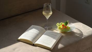 Ein offenes Buch auf einem Tisch mit einem Glas Weißwein und einer Obstplatte.