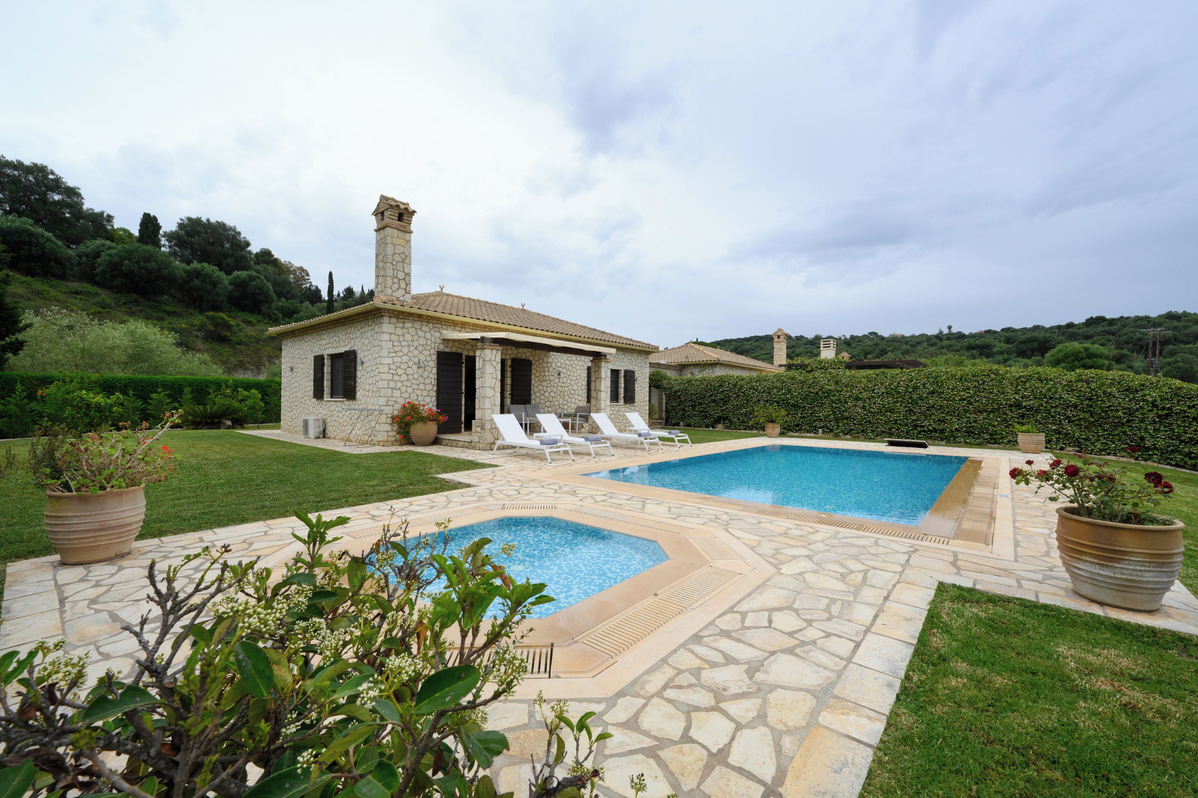 Une maison en pierre avec une piscine et des chaises longues.