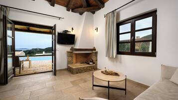 Una habitación acogedora con chimenea de piedra, televisor montado en la pared y vistas a una piscina.