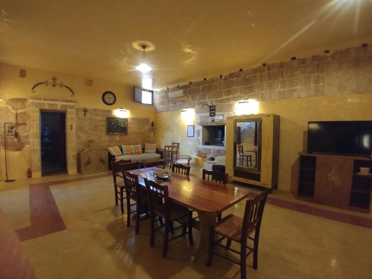 Un comedor con mesa y sillas de madera, una pared de piedra y un televisor.