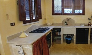 A compact kitchen with a gas stove, a sink, and a window with blinds. - MASSERIA LA MAESTA' 1511 (Sannicola)
