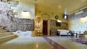 A spacious room with a stone wall, a wooden staircase, a fireplace, and a bed. - MASSERIA LA MAESTA' 1511 (Sannicola)