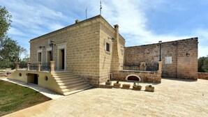 A stone building with a balcony and steps leading to a door. - MASSERIA LA MAESTA' 1511 (Sannicola)