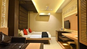 A modern hotel room with a bed, a sofa, a desk, and a TV. - HOTEL ROYAL COTTAGE (Kanpur)
