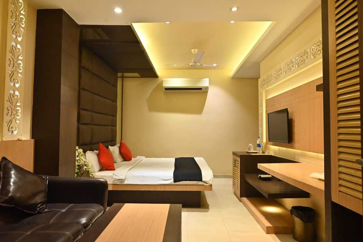 A modern hotel room with a bed, a sofa, a desk, and a TV.