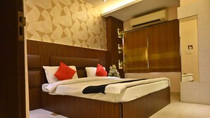 A modern hotel room with a large bed, wooden headboard, and a geometric patterned wall. - HOTEL ROYAL COTTAGE (Kanpur)