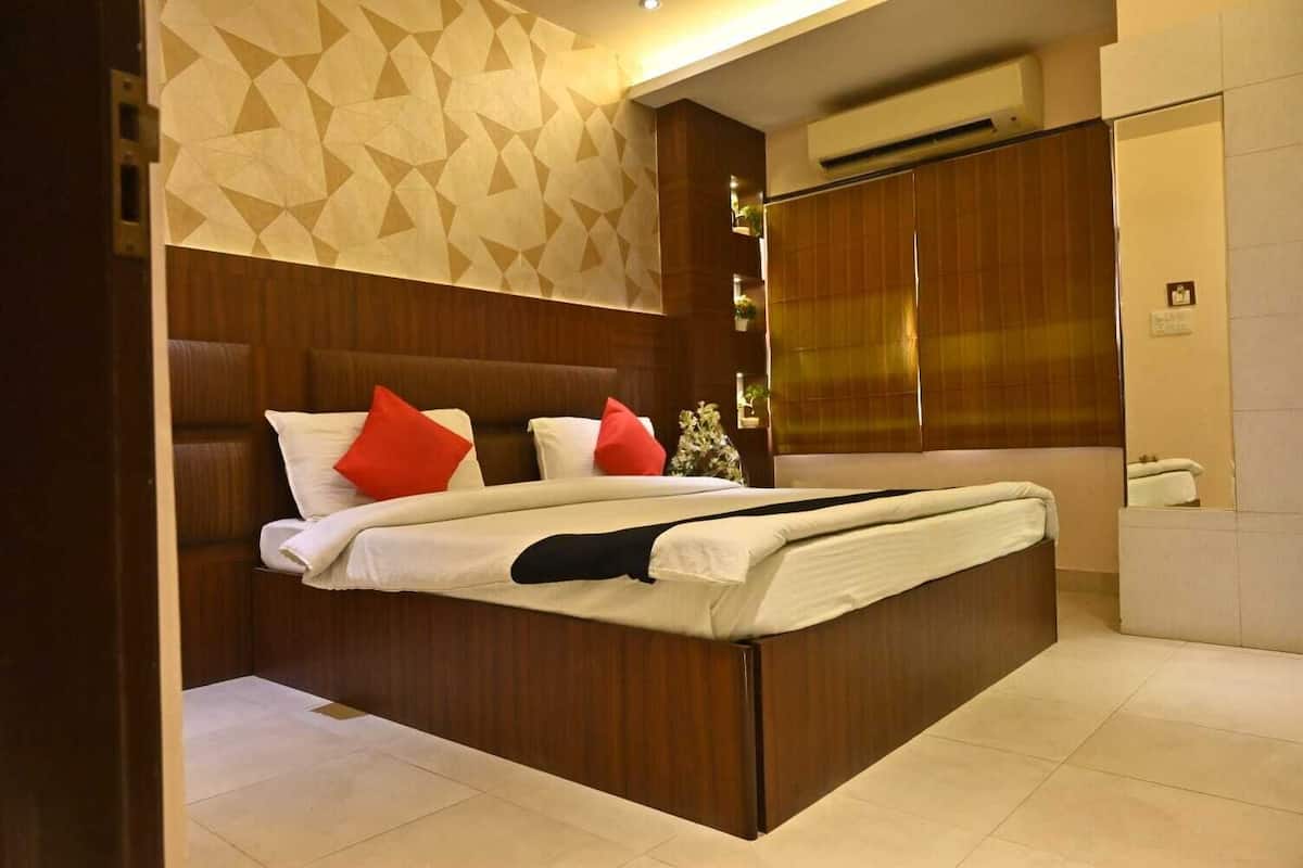 A modern hotel room with a large bed, wooden headboard, and a geometric patterned wall.