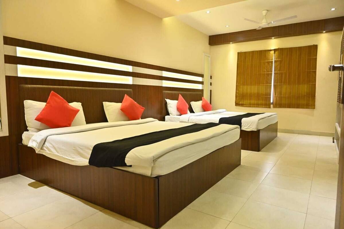 A hotel room with two beds, wooden headboards, and a large window with blinds.